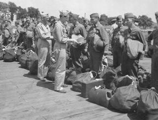 Chaplain Maj. Wesley Gebhard (officer at left) with his colleague, Chaplain Capt. Dunstan W. Smith, at the Fort Slocum dock distributing Bibles to soldiers leaving for combat assignments during the Second World War.